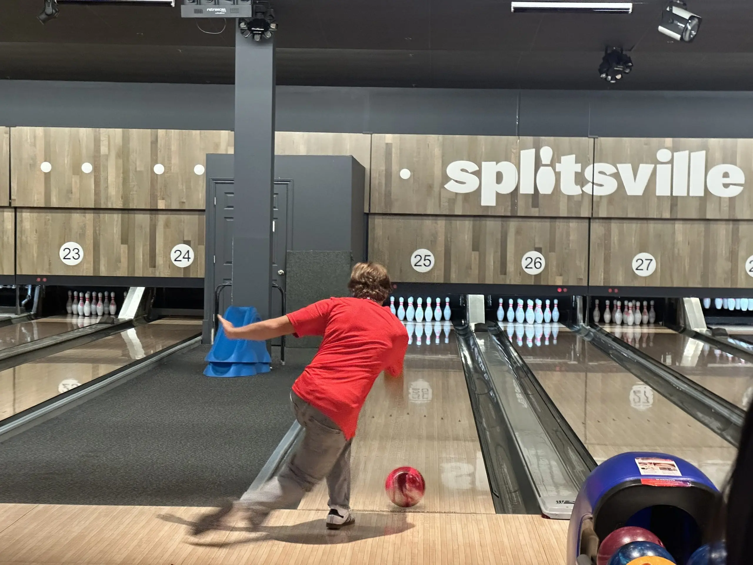 Young bowler in a red shirt throwing a ball down the lane at Splitsville