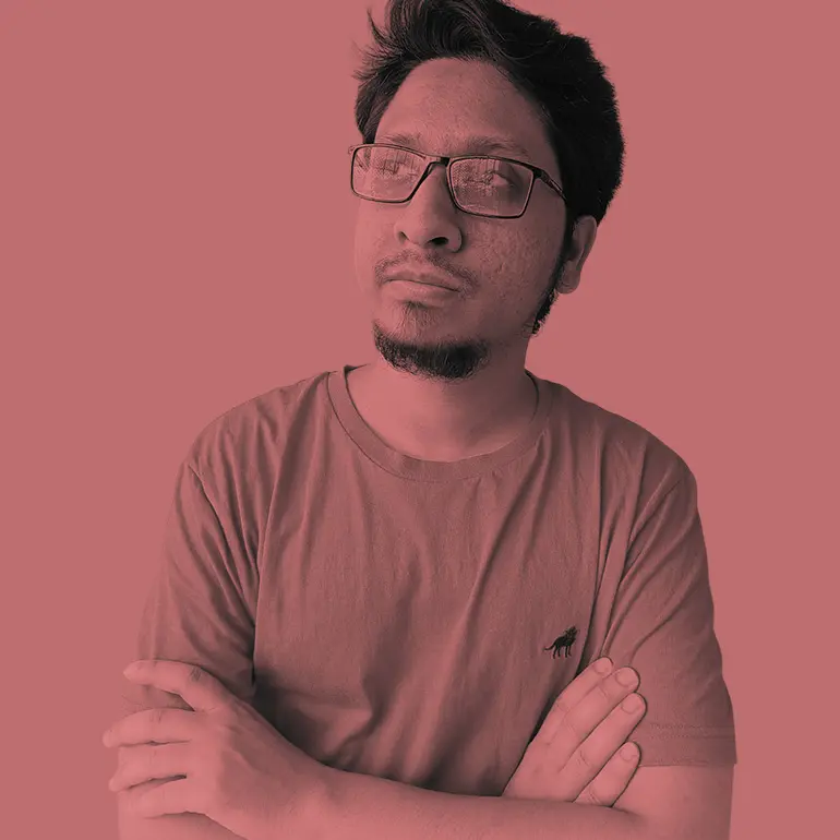Man with glasses and goatee wearing a t-shirt with arms crossed, looking away