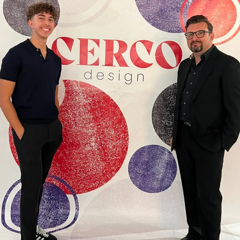 Two men stand in front of a CERCO design banner with red and purple circles.