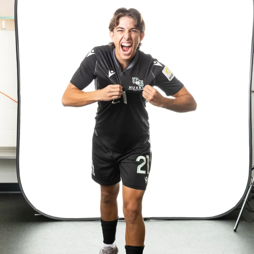 Soccer player with number 21 on black jersey and shorts chews mouth open in excitement