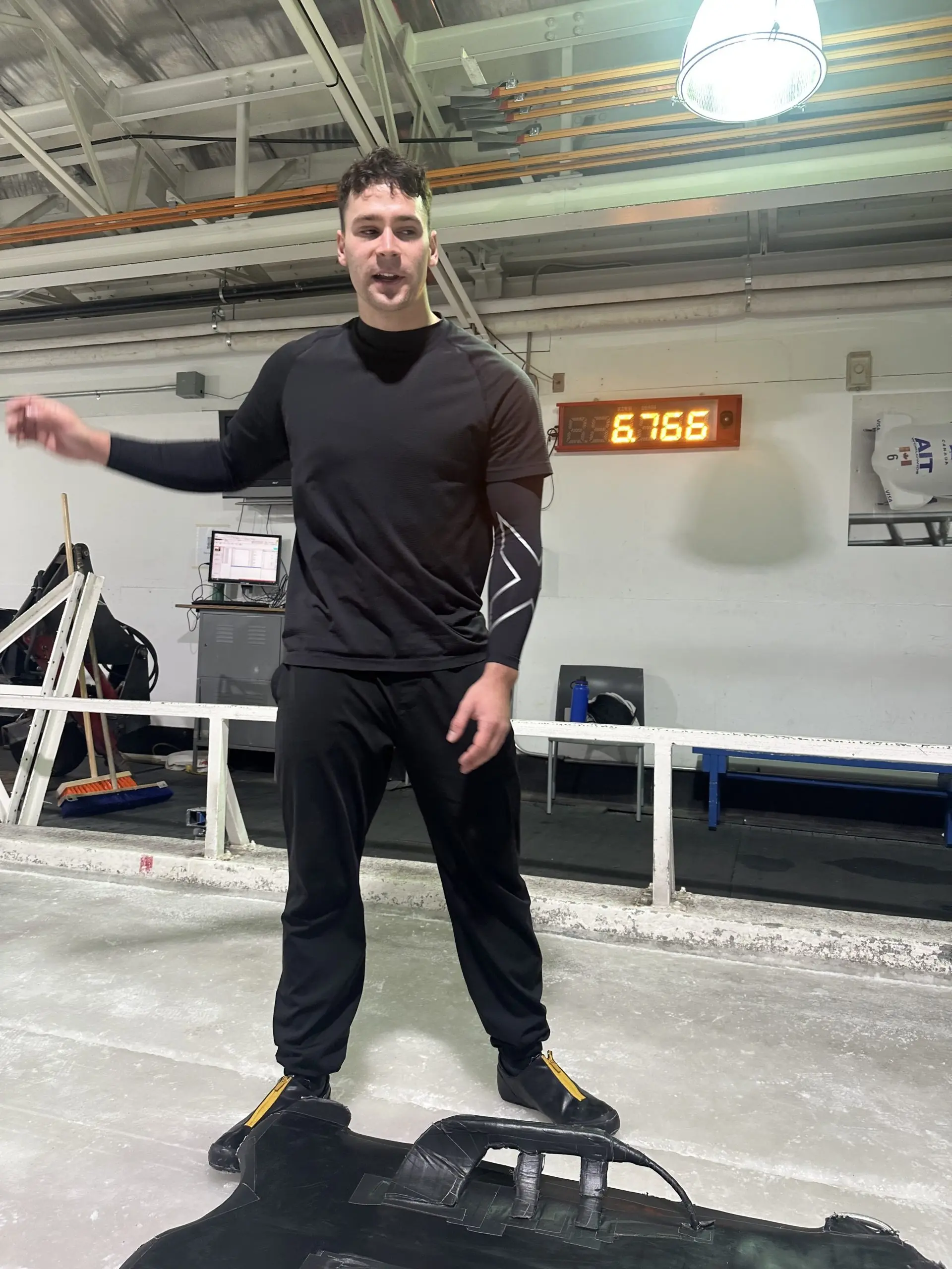 Hockey player in training gear standing on an ice rink near a timer displaying 6.766.