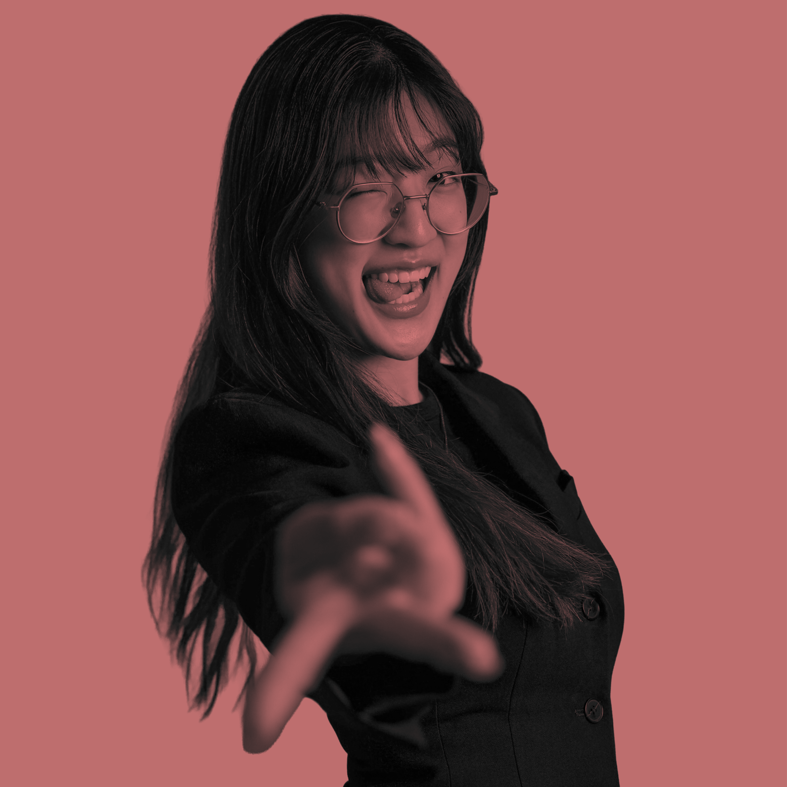 Young woman in glasses winks and points, smiling broadly.