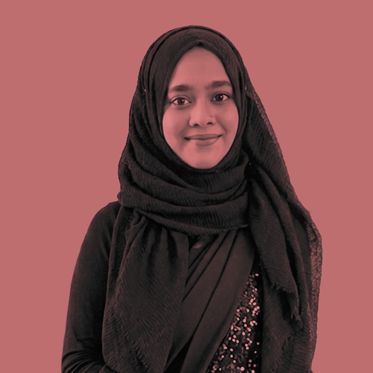 A young woman wearing a black hijab and sparkly dress smiles.