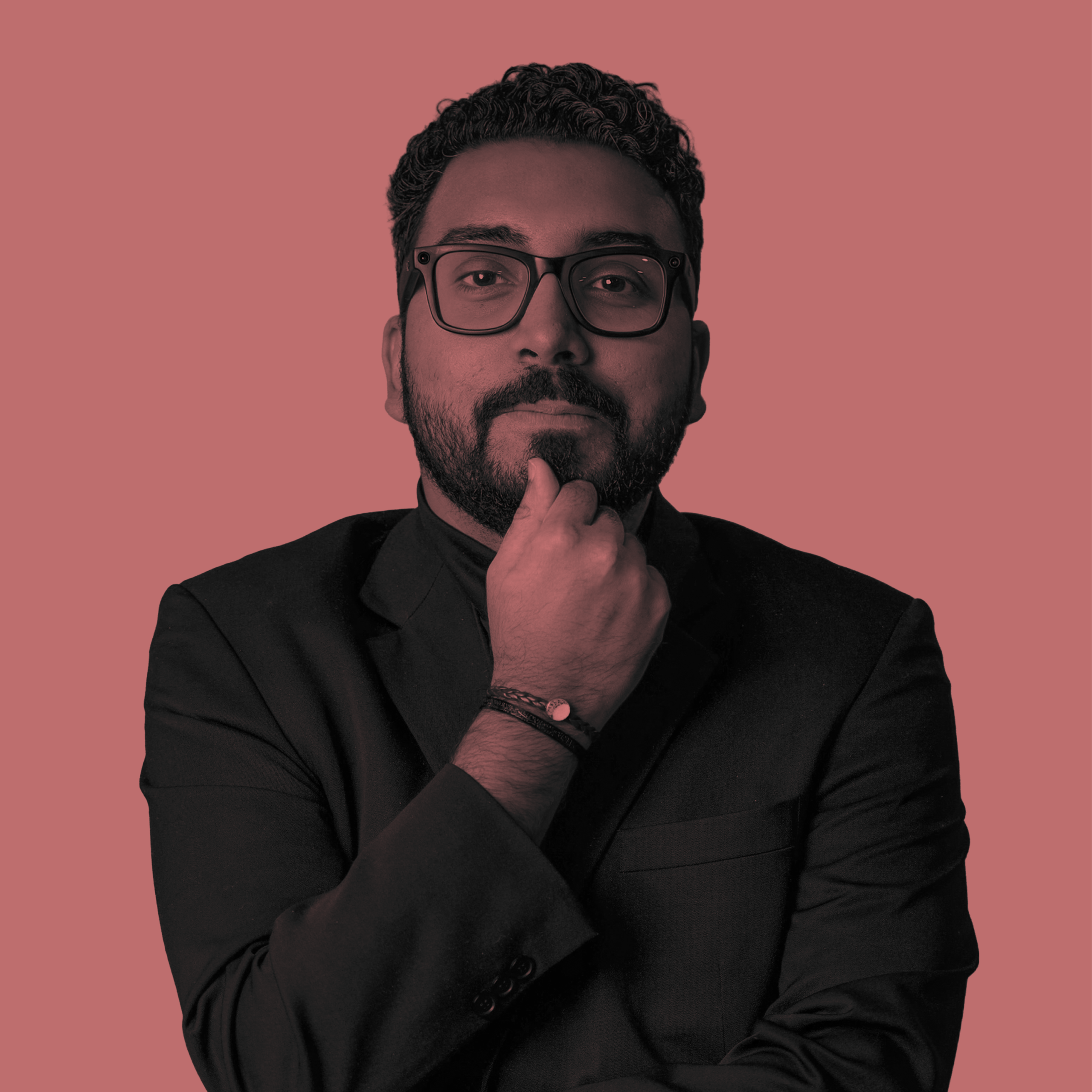 Man in suit and glasses with hand to chin, thinking pose