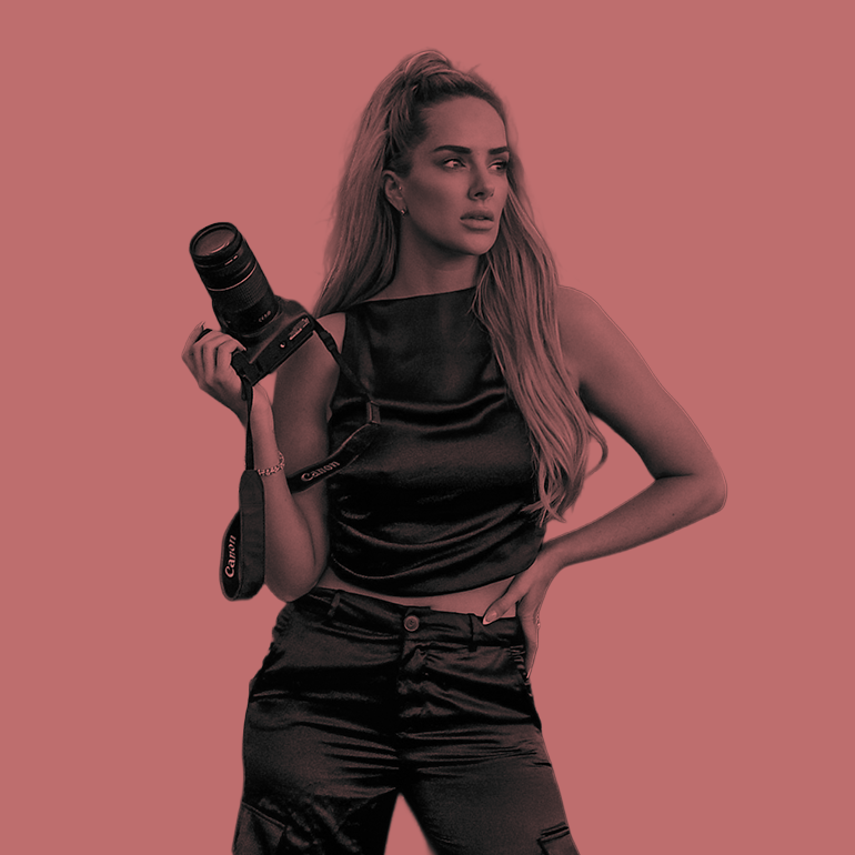 Woman photographer holding Canon camera with long blonde hair and black outfit